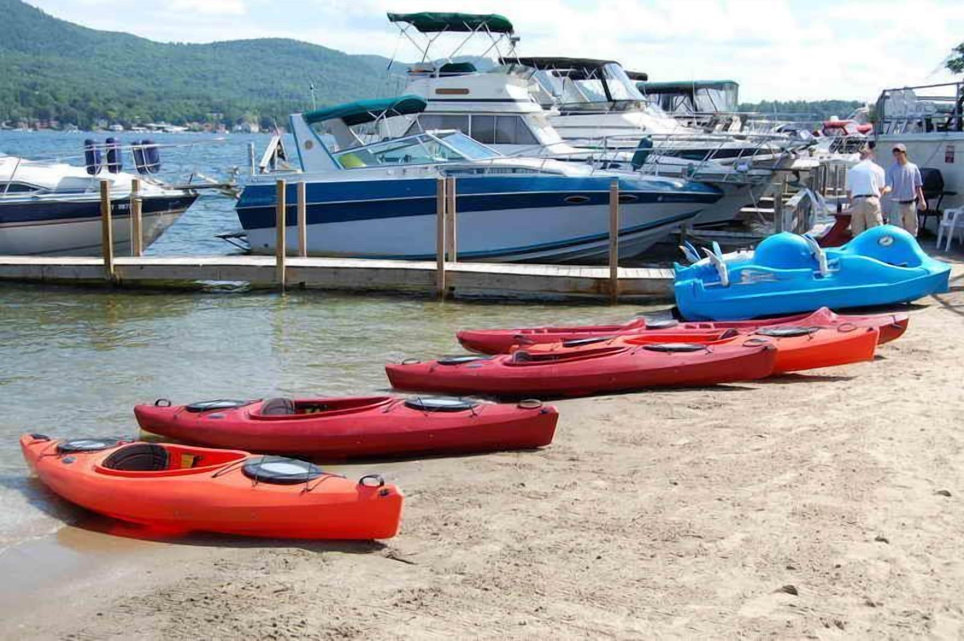 A marina with boats docked and kayaks lined up on the shore.