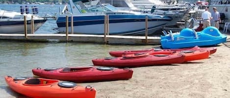 A marina with boats docked and kayaks lined up on the shore.