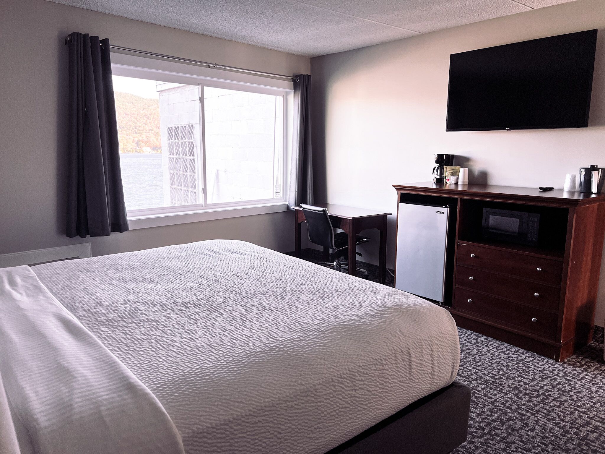 Une chambre d’hôtel équipée d’un lit, d’un bureau, d’une télévision et d’un réfrigérateur.