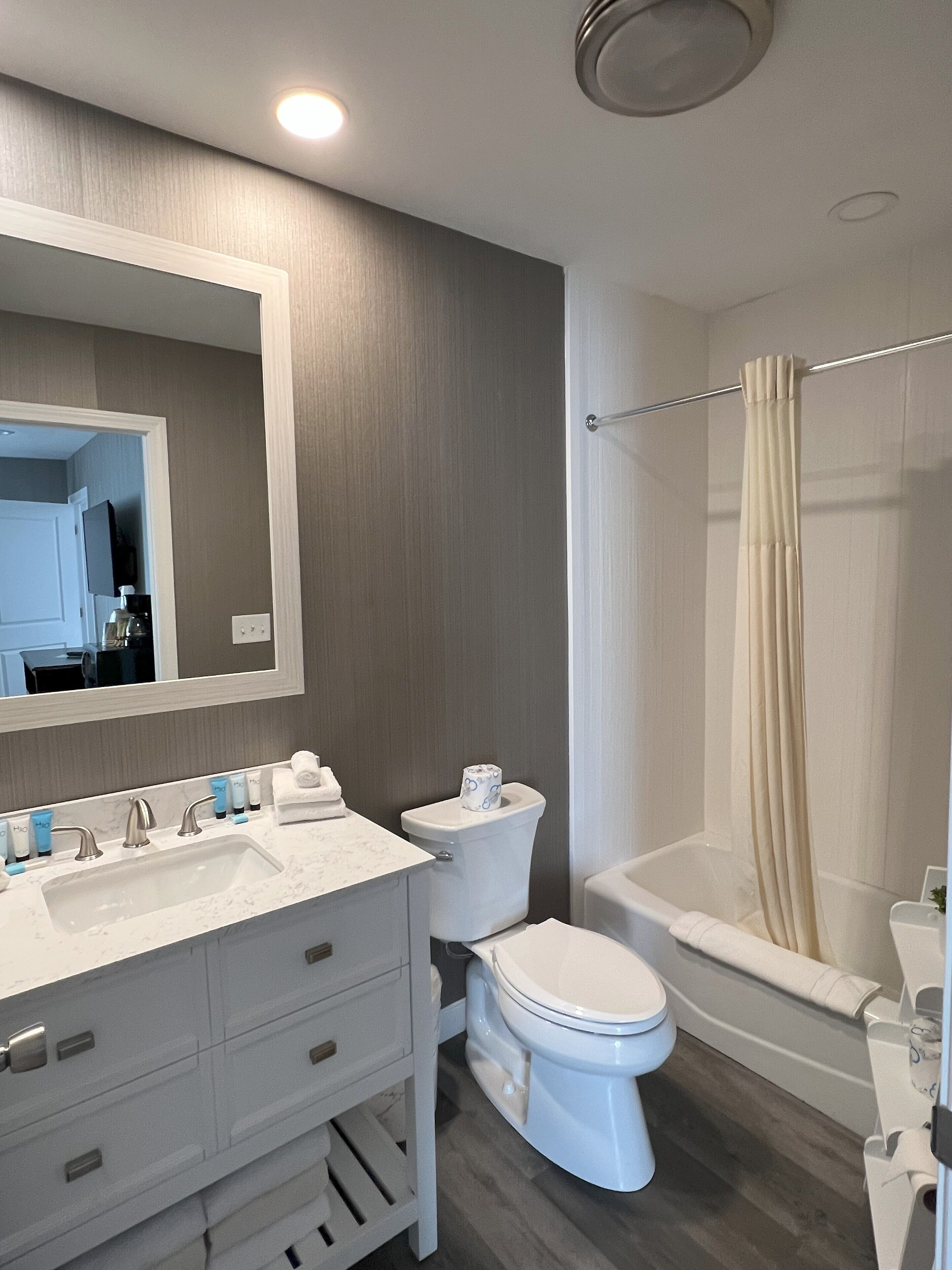A modern bathroom with a vanity, sink, toilet, and bathtub.