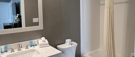 A modern bathroom with a vanity, sink, toilet, and bathtub.