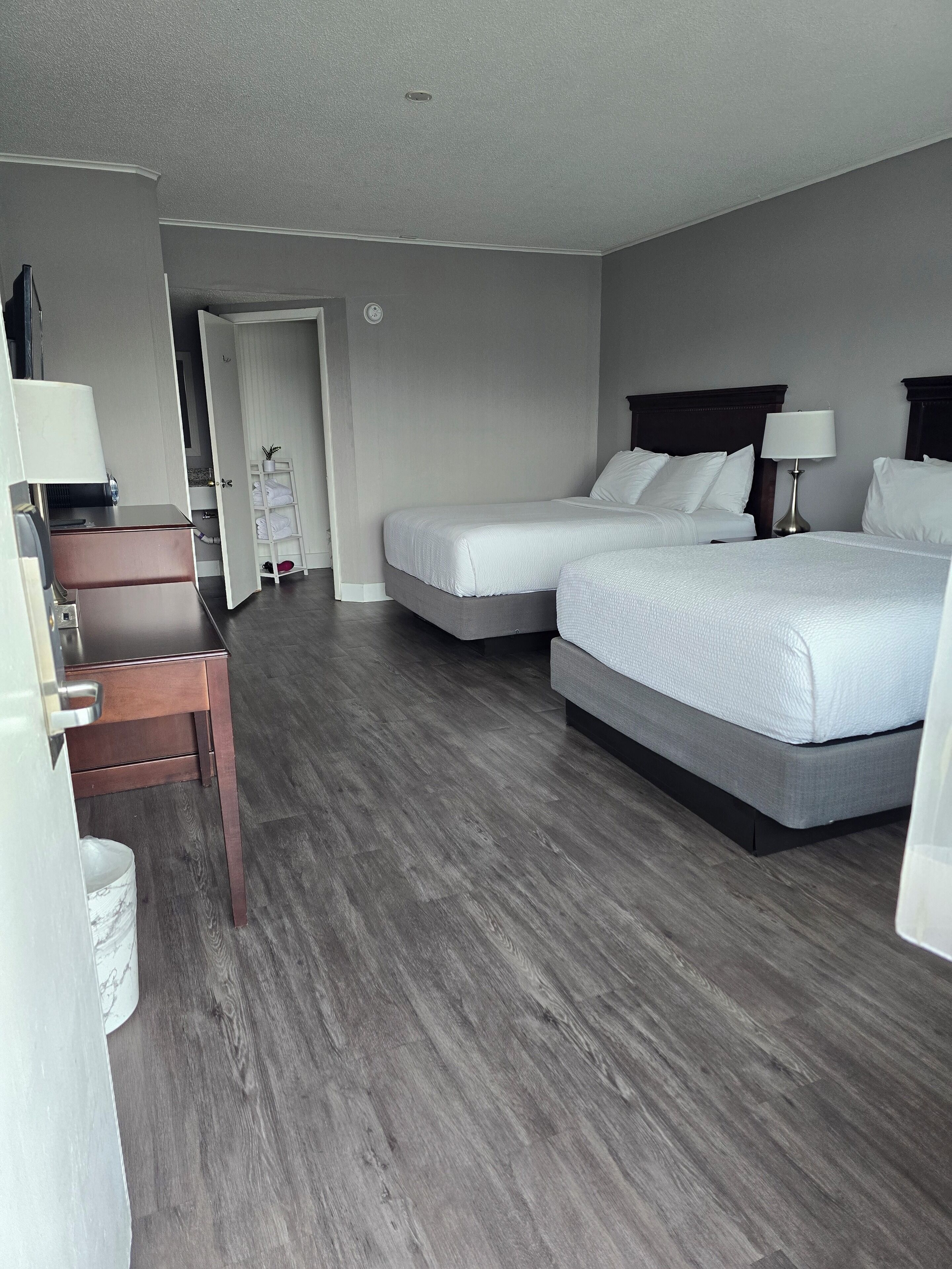 Ett hotellrum med två sängar, ett skrivbord, en stol och en garderob.