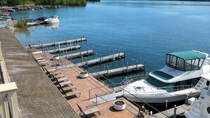 A marina with docked boats, a covered seating area, and a view of a lake with mountains in the background. - The Georgian Lakeside Resort (Lake George)
