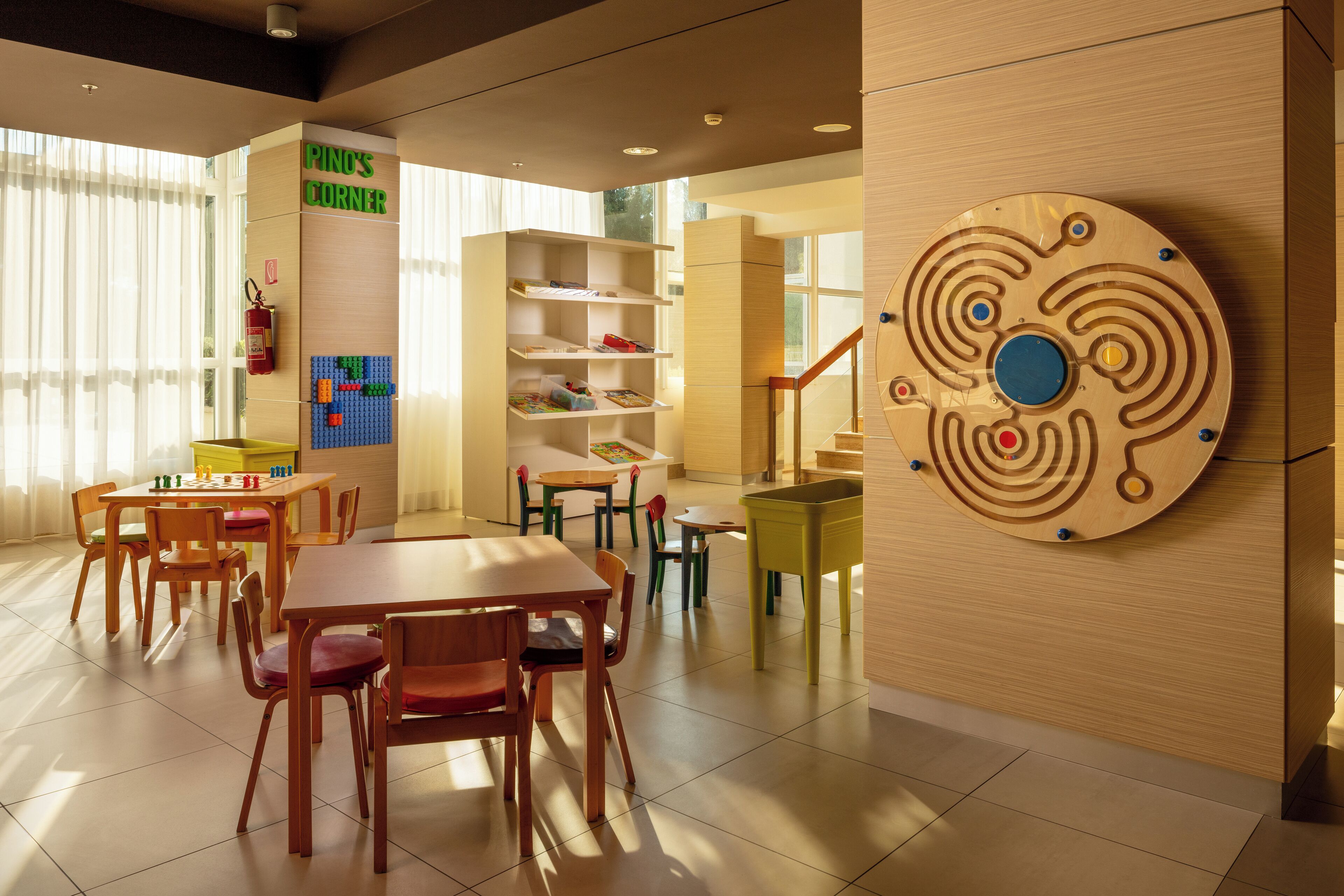 A modern children's play area with tables, chairs, and shelves.