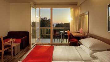 Une chambre d’hôtel comprenant un lit, un bureau, une chaise, un canapé et un balcon avec vue sur l’extérieur.