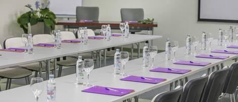 A conference room with long tables, chairs, water bottles, and glasses.