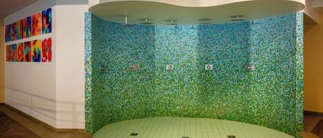Une pièce circulaire avec un mur décoré de mosaïques, un sol carrelé et un plafond blanc.
