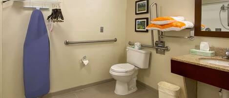 Et badeværelse med toilet, vask og brusebad. Der er en håndklædestige med et blåt håndklæde og en brusekurv med et orange håndklæde.