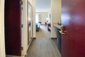 A hotel hallway with a bed, desk, and a mirror.