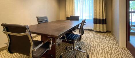Une salle de conférence avec une grande table, quatre chaises et un sol recouvert de moquette.