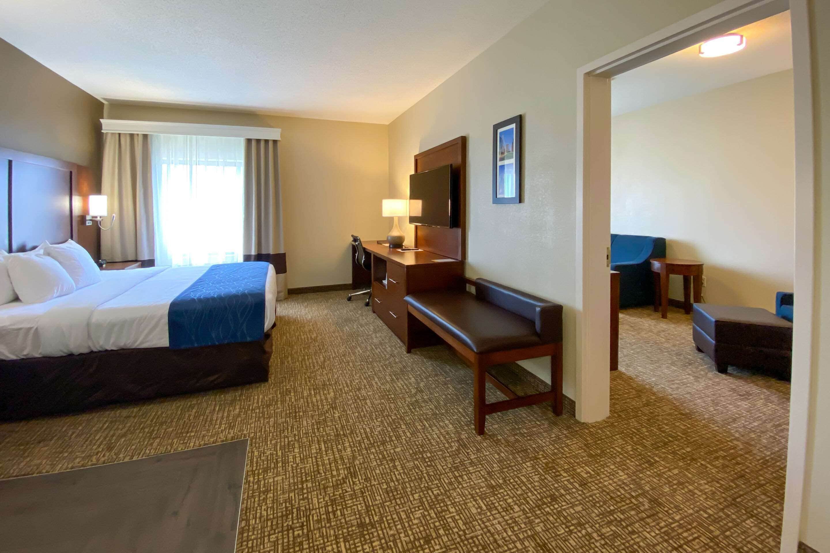 Una habitación de hotel con cama, escritorio, silla y televisor.
