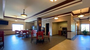 A spacious lobby with wooden flooring, red and black chairs, a coffee station, and a television. - Comfort Inn East Windsor - Springfield (East Windsor)