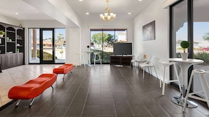 A spacious living area with a large TV, seating, and a view of the outdoors. - Ramada by Wyndham Marina (Marina)
