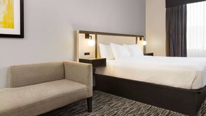 A hotel room with a bed, a sofa, a nightstand, and a framed picture on the wall. - Ramada by Wyndham Marina (Marina)
