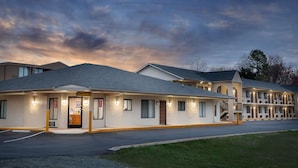 Un motel con una oficina central, varias habitaciones para huéspedes y un estacionamiento.