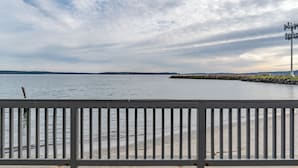 A waterfront view with a wooden railing, calm water, and a cloudy sky. - Water Front Inn (Port Townsend)