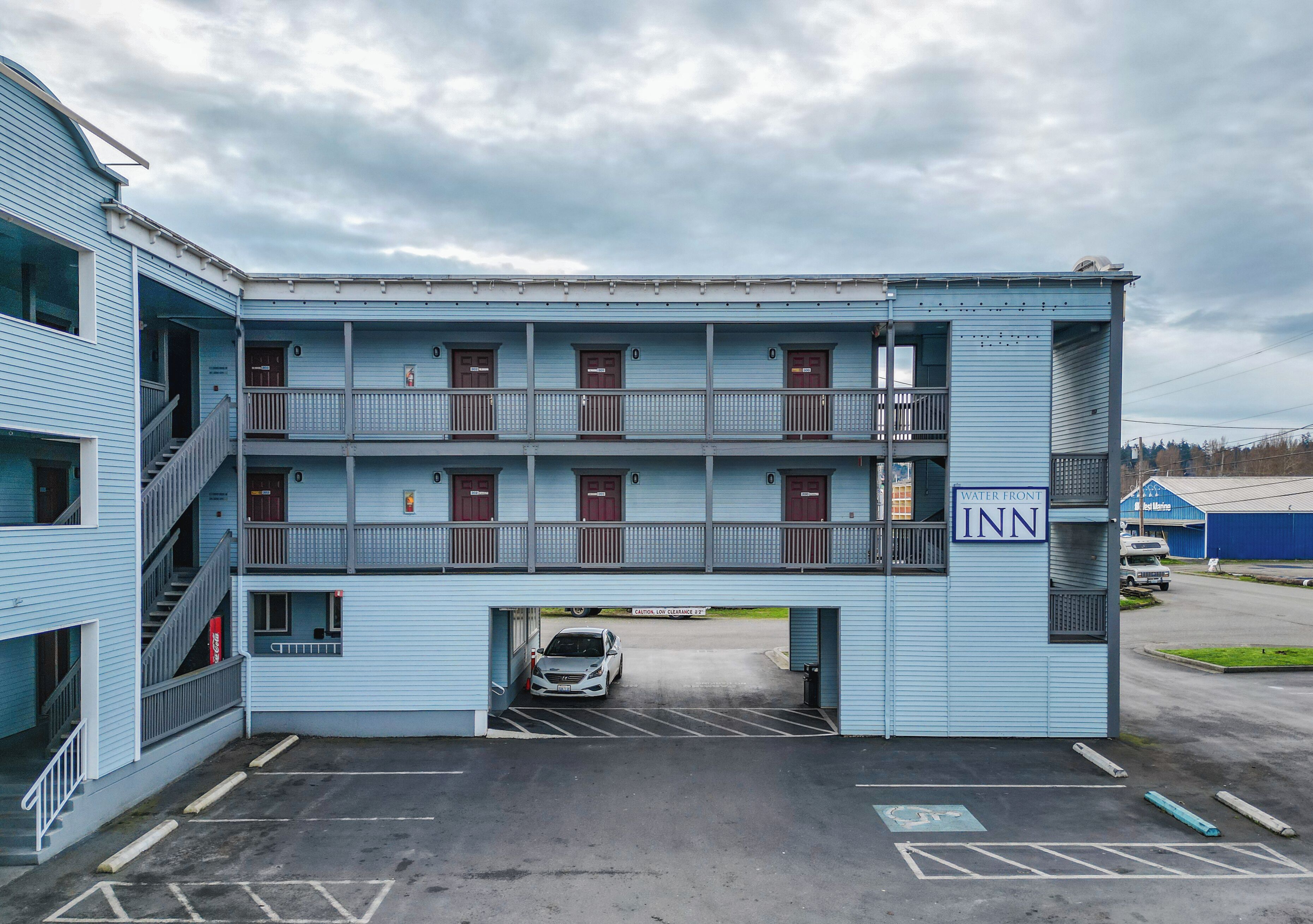 Ett motell i två våningar med en balkong på andra våningen, en parkeringsplats och en skylt som visar att det är ett hotell vid vattnet.