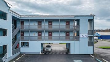 Ett motell i två våningar med en balkong på andra våningen, en parkeringsplats och en skylt som visar att det är ett hotell vid vattnet.