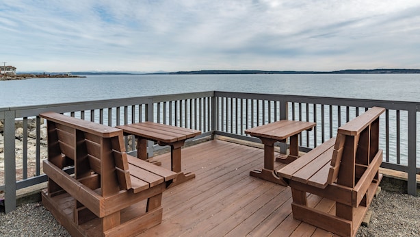A wooden deck with picnic tables overlooking a body of water. - Water Front Inn (Port Townsend)