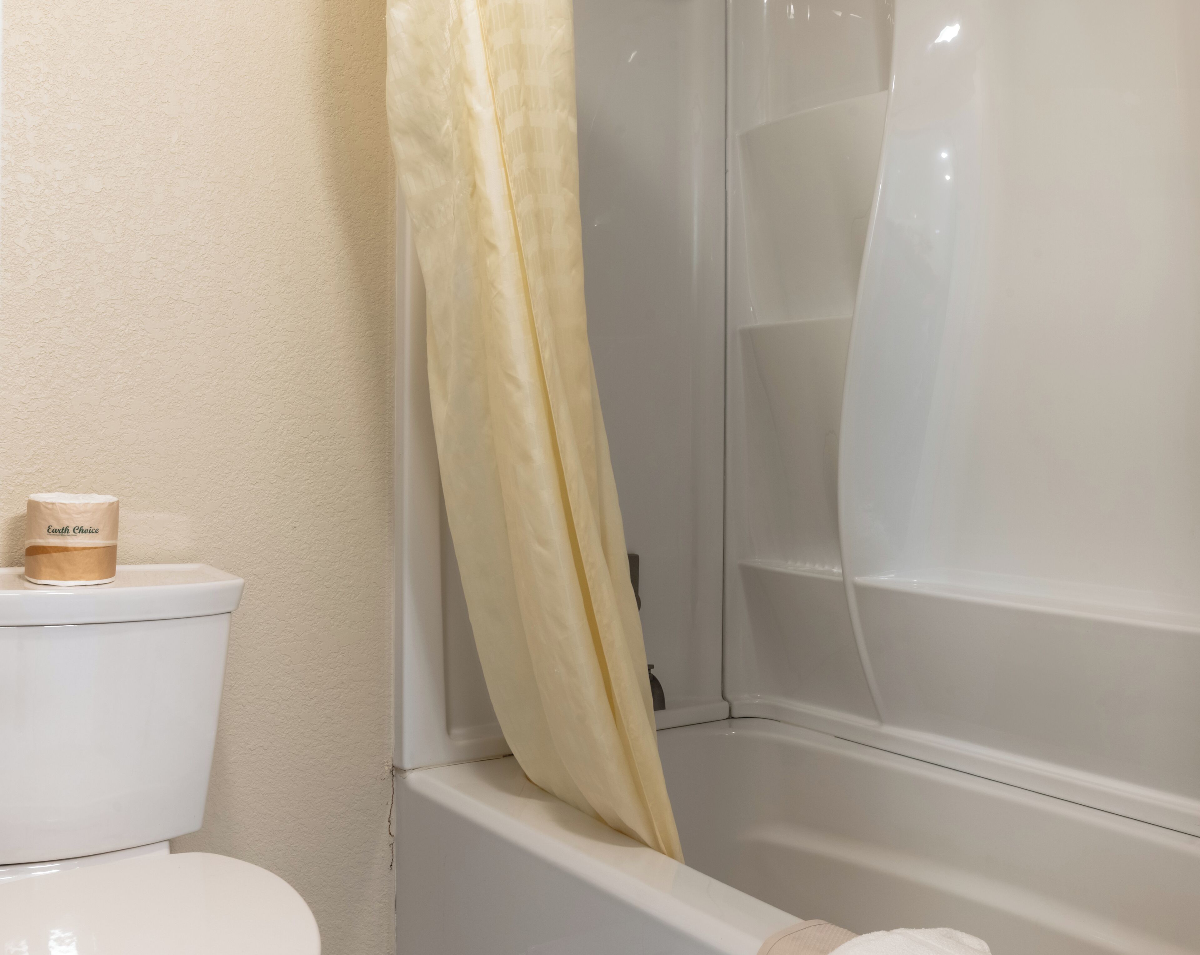 A bathroom with a toilet, a shower curtain, and a bathtub.