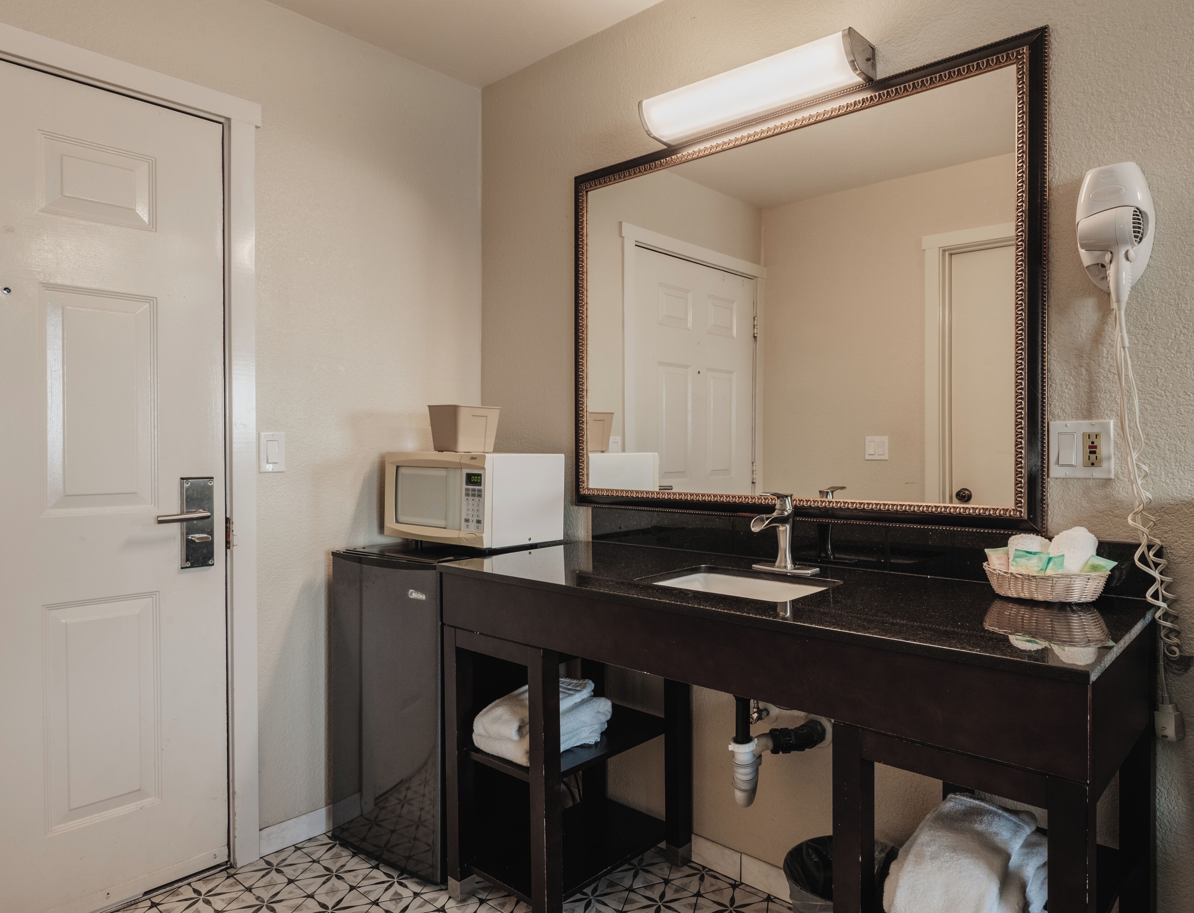 Une salle de bain équipée d’un lavabo, d’un miroir, d’un four à micro-ondes et d’un sèche-cheveux.