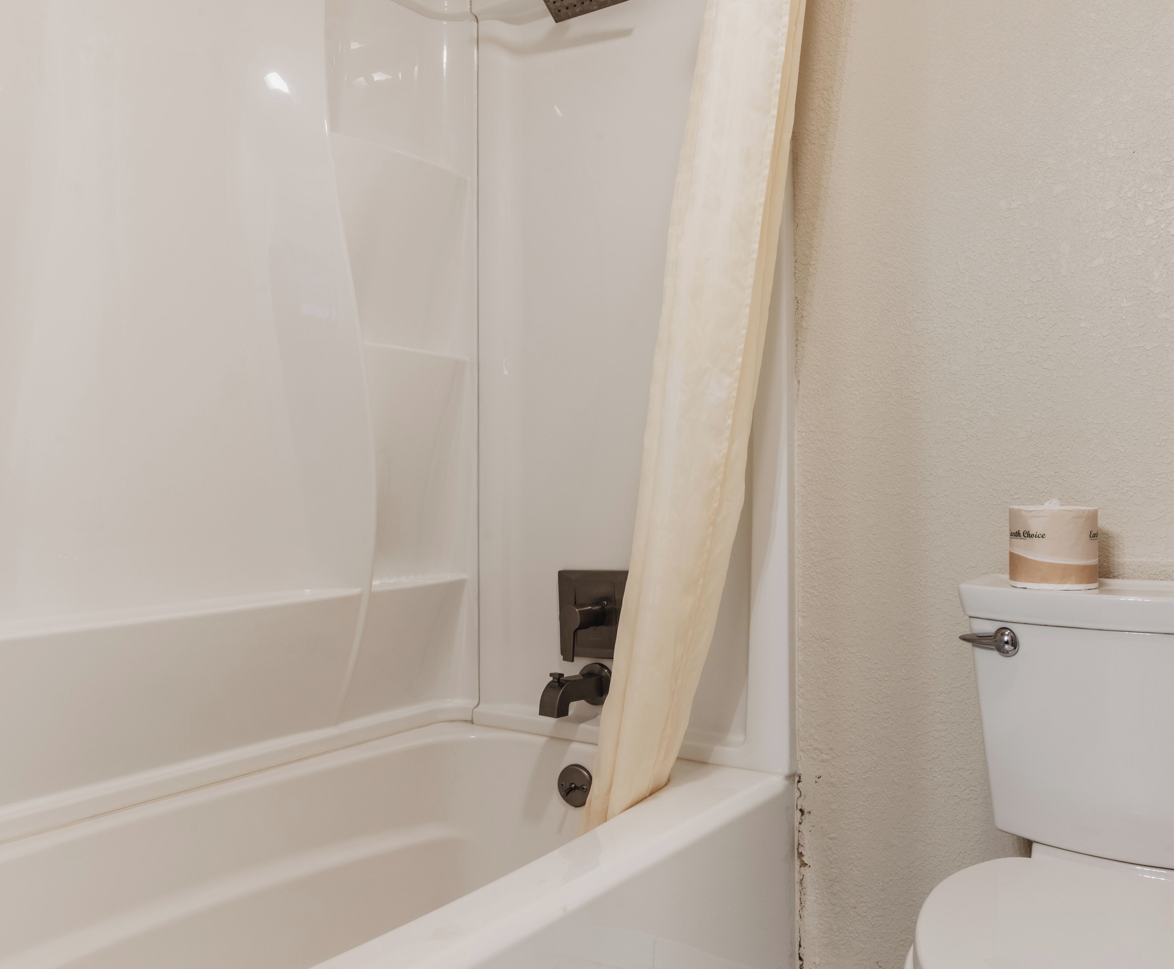 A bathroom with a bathtub, toilet, and a shower curtain.