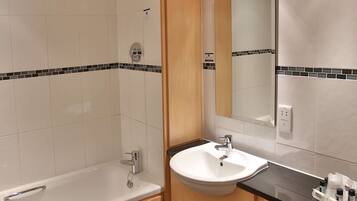 Een moderne badkamer met een bad, wastafel en toilet.