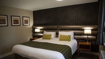 A neatly made bed with a patterned bedspread, two bedside lamps, and a headboard with a geometric pattern.