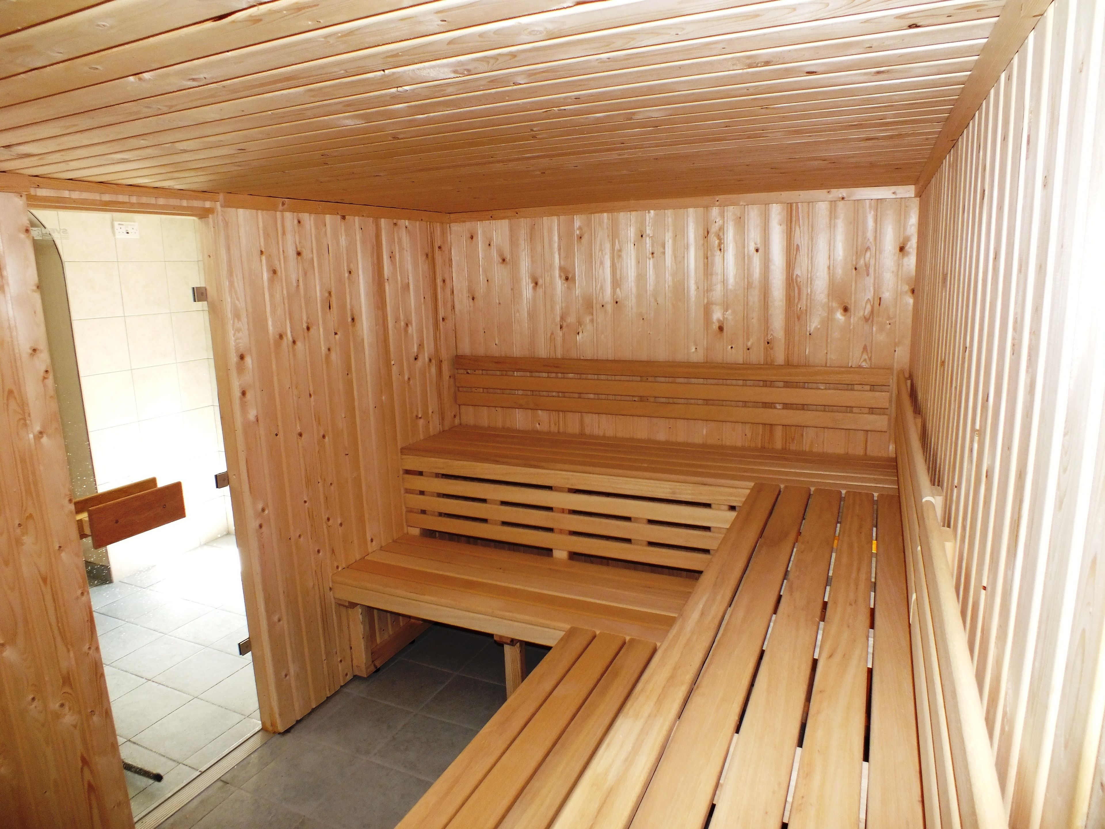 Una sauna de madera con bancos y suelo de baldosas.