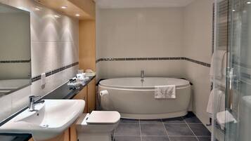 Ein modernes Badezimmer mit Badewanne, Toilette, Waschbecken und einem großen Spiegel.