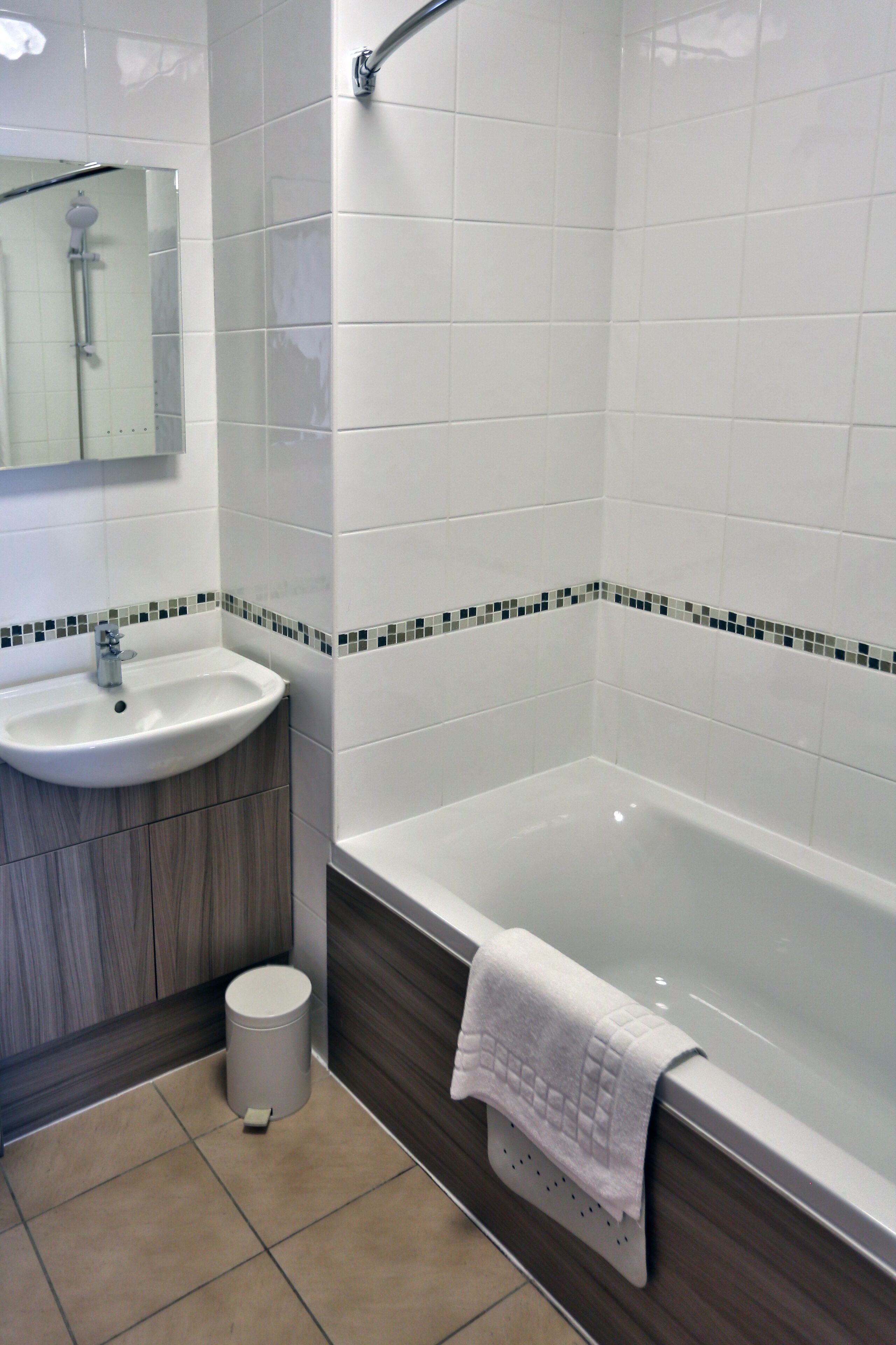 A bathroom with a white sink, a bathtub, and a mirror.