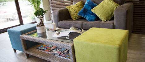 A living room with a grey sofa, a coffee table, and a blue ottoman.