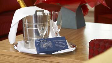 A dining table with a champagne bottle, two glasses, and a blue card on a tray.