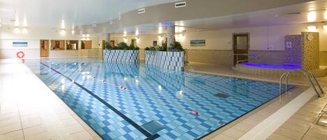 An indoor swimming pool with a checkered tile pattern, a changing room area, and a sauna.