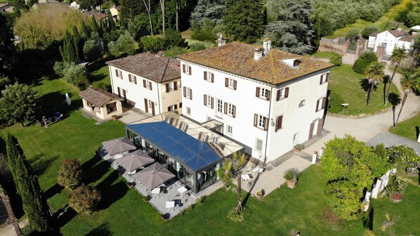 A large, two-story building with a spacious patio area and multiple outdoor seating arrangements. - Albergo Villa Marta (Lucca)