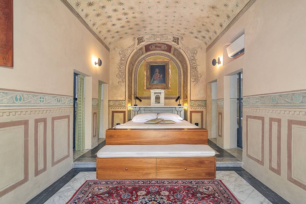 A hotel room with a large bed, a small altar, and a ceiling with star patterns.