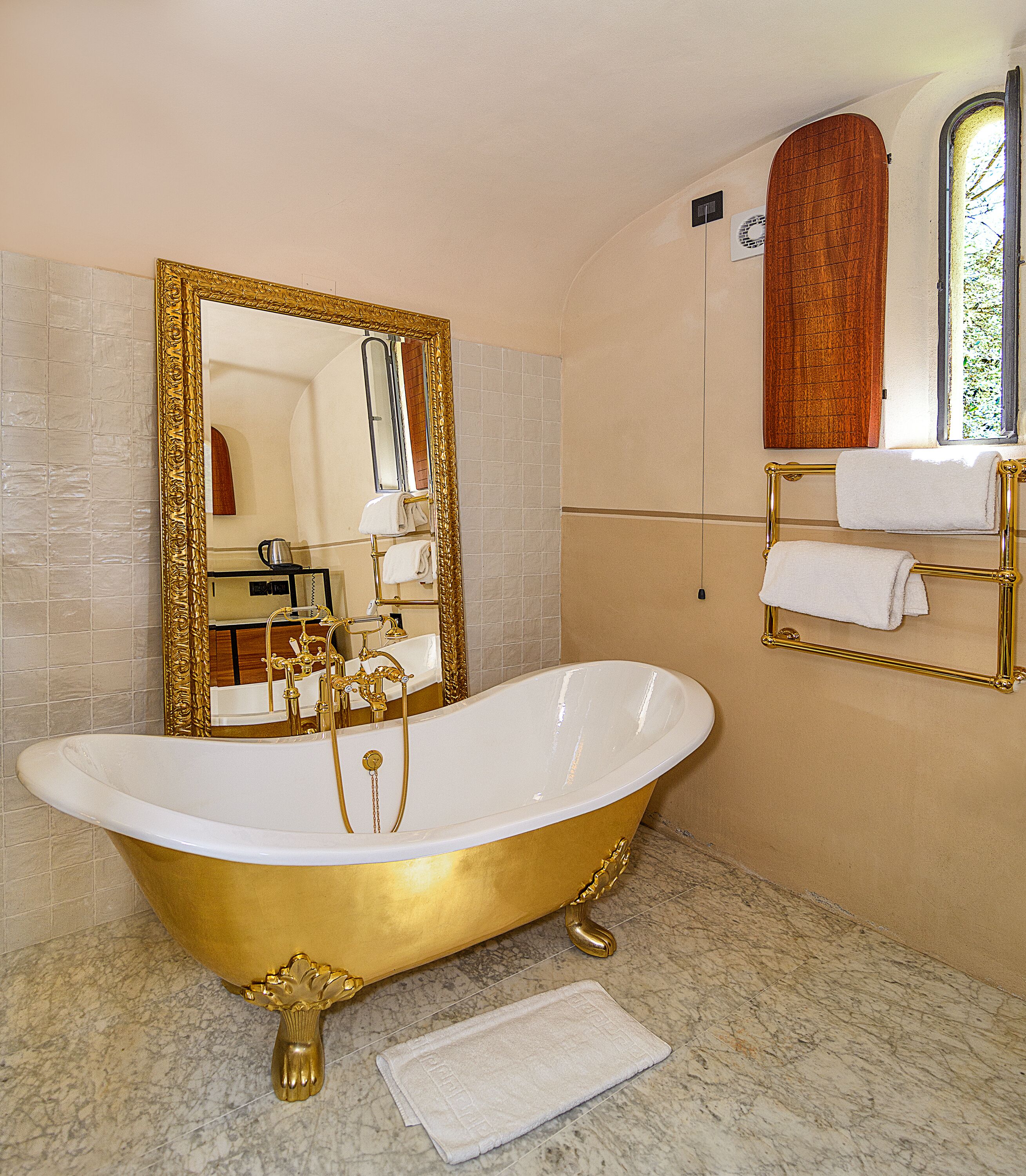 Une salle de bain avec une baignoire sur pieds, un grand miroir et un porte-serviettes.