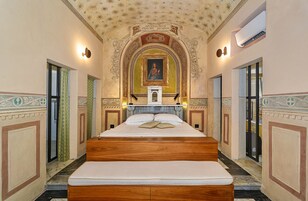 Un letto grande e centrale con poggiatesta in legno, affiancato da due porte su ciascun lato.