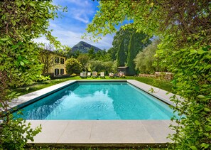 A rectangular swimming pool with a clear blue water surface, surrounded by lush greenery and a stone deck. - Albergo Villa Marta (Lucca)