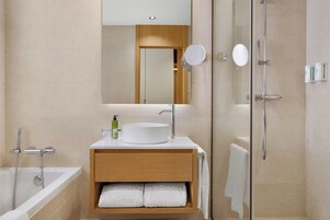 A modern bathroom with a bathtub, a sink, a mirror, and a shower.
