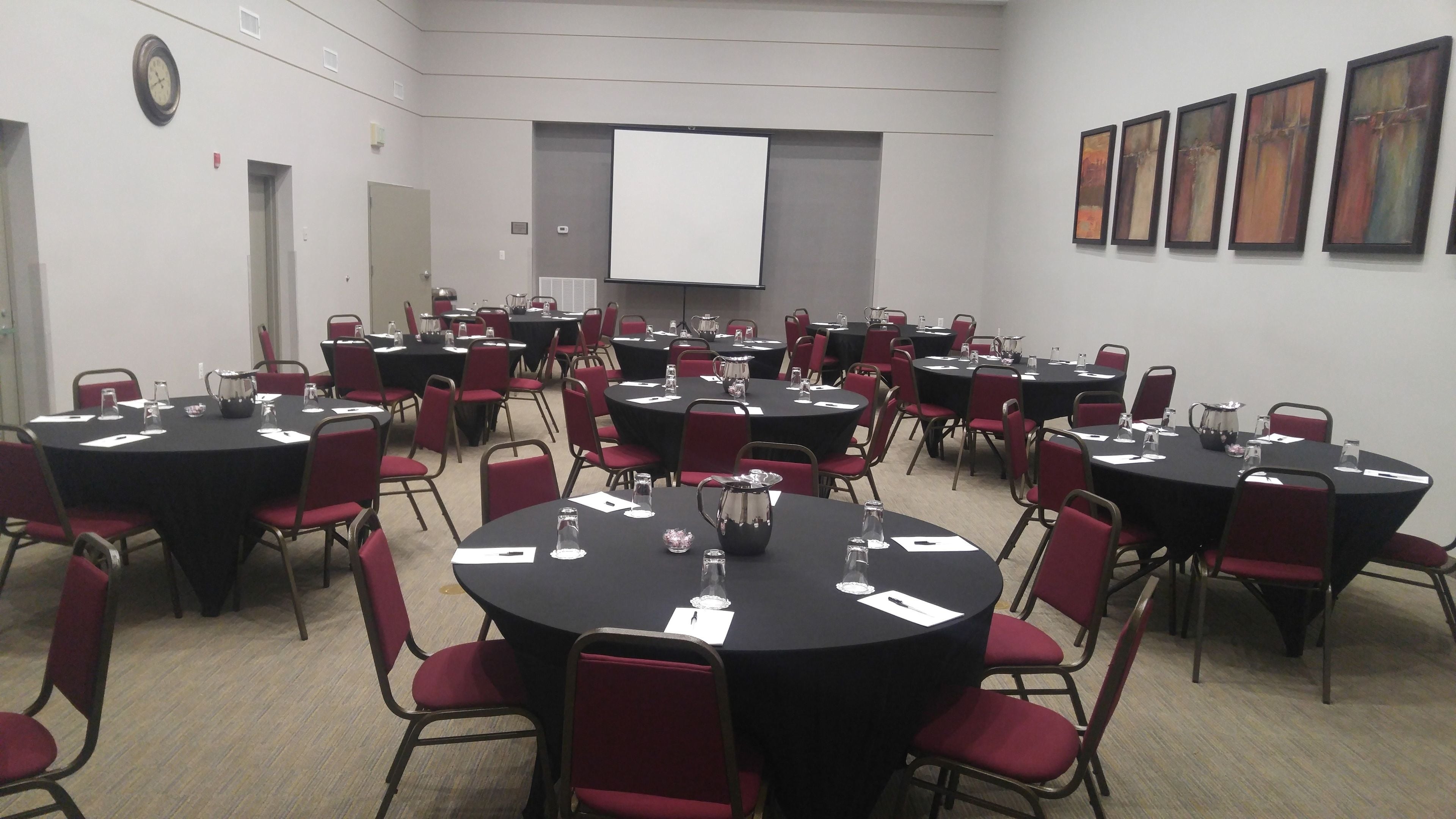 A conference room with multiple tables and chairs, equipped with water pitchers and name cards.