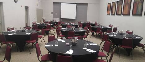 A conference room with multiple tables and chairs, equipped with water pitchers and name cards.