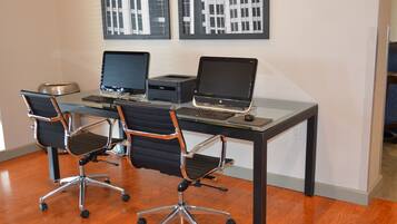 Ein moderner Arbeitsraum mit zwei Laptops, einem Desktop-Computer und zwei Bürostühlen.