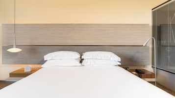 Une chambre d’hôtel moderne avec un grand lit, une table de chevet avec une lampe et une petite table de nuit avec un téléphone.