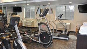 Ein Fitnessstudio mit Fahrrädern, Laufbändern und einem Fernseher an der Wand.