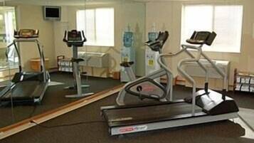 Un gimnasio con cintas de correr, bicicletas estáticas y un espejo grande.