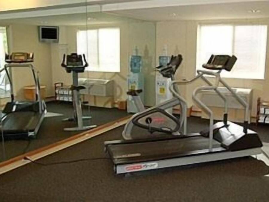Un gimnasio con cintas de correr, bicicletas estáticas y un espejo grande.