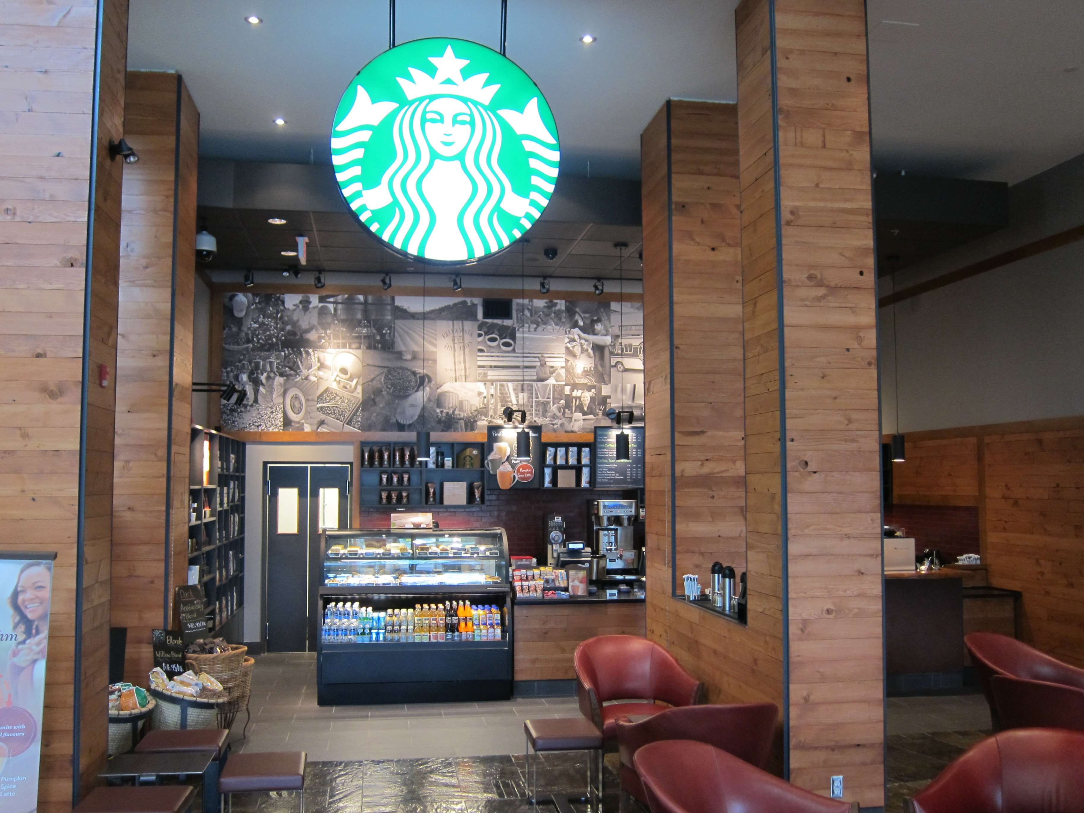 A Starbucks coffee shop interior with seating, a display case, and a wall with images.