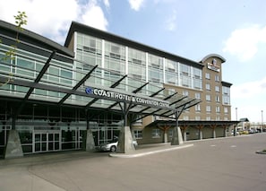 Un hotel con diseño moderno, que presenta una entrada cubierta y un cartel que dice 'Coast Hotel & Convention Centre'.