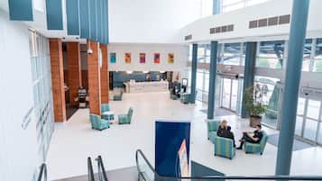 A spacious lobby with a reception desk, seating area, and large windows.